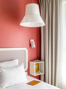 尼斯OKKO Hotels Nice Aéroport的一间卧室设有红色墙壁、一张床和一盏灯