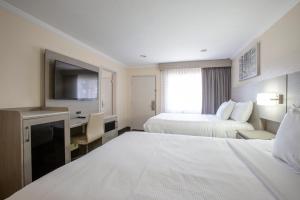 弗拉格斯塔夫阿斯本弗拉格斯塔夫/大峡谷旅馆套房酒店的酒店客房设有两张床、一张桌子和一台电视。