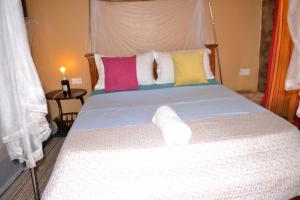 KisoroMondi Lodge Kisoro的一间卧室配有一张带色彩缤纷枕头的大床
