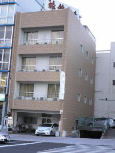 广岛天龙日式旅馆的一座高大的砖砌建筑,前面有汽车停放