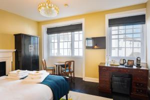 莱姆里吉斯Lyme 1 Hotel的一间卧室配有一张床、一张书桌和两个窗户。