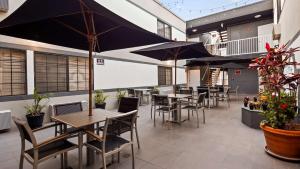 洛杉矶SureStay Hotel by Best Western Beverly Hills West LA的一间带桌椅和遮阳伞的餐厅