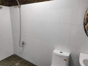 美岸RedDoorz @ Villa E Mansion的白色瓷砖浴室设有卫生间和淋浴。