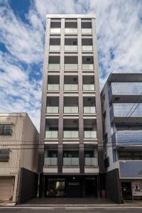 广岛HOTEL SUITE HIROSHIMA YOKOGAWA的一座高大的灰色建筑,背后是天空