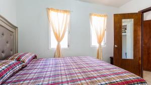 East End VillageMoonlight Cottage的一间卧室设有一张床和两个窗户。