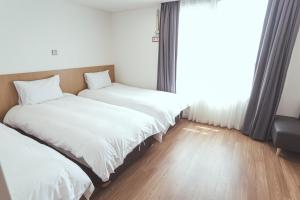 西归浦市Kenny Stay Jeju Mosulpo的带窗户的客房内的两张床