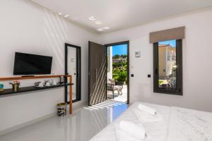 蒂锡利维Sunny Garden Hotel的白色的客房设有1张床、1台电视和1个阳台。