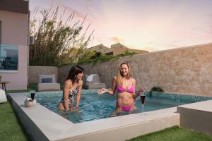 马莱迈Aegean Breeze Luxury Apartments的两名女性穿着泳衣进入游泳池