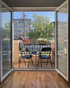 克拉多沃Danubiana Apartments的阳台配有两把椅子和一张桌子,阳台设有窗户