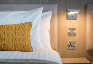 曼彻斯特Maldron Hotel Manchester City Centre的一张带白色床单和黄色枕头的床