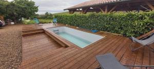 CharentayLa Maison des Vignes的木制甲板上的游泳池,配有两把椅子