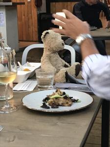 昂迪兹L'Hotel du Garage des Cevennes的一只泰迪熊坐在桌子上,拿着一盘食物