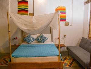 蒙波斯Pueblito Magico Hostel - Mompox的一张带天蓬的床,位于一个沙发的房间