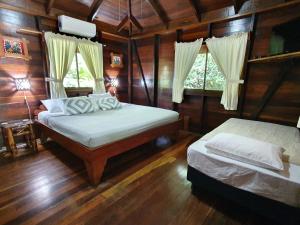 别霍港卡里布鲁海滩及丛林度假酒店的配有木墙和木地板的客房中的两张床