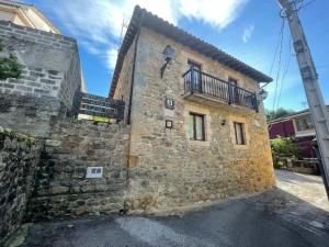 AlcedaApartamentos rurales La Casa Vieja De Alceda的一座石头建筑,旁边设有阳台