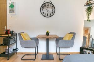 英格堡Spirit Apartments - Neben dem Titlis - Parkplatz的一张桌子、两把椅子和墙上的时钟