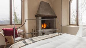加比亚诺盖比亚诺城堡酒店的一间卧室设有壁炉、一张床和一把椅子