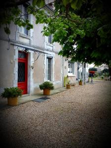Saint-Martin-de-Gurçon安妮住宿加早餐旅馆的一座种植盆栽植物的建筑上的红门