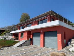 BelleriveVilla au bord du lac de Morat avec vue imprenable的一间红色的房子,前面有两个车库门
