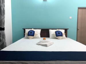 尼甘布Royal City Inn的一张带白色床单和蓝色枕头的床