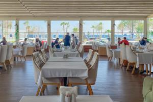 安塔利亚水晶海滨酒店的一间设有白色桌椅的餐厅,供有饭吃的人用餐