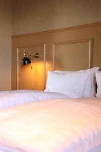 阿克雷里阿库雷里酒店的一张铺有白色床单的床和墙上的灯