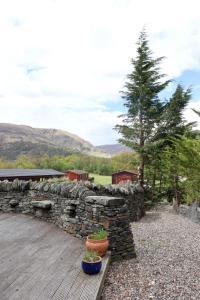 格拉斯哥Lodge 38 Rowardennan , Loch Lomond的木甲板上有一堵石墙和两株盆栽植物