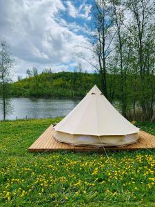 奥泰佩Murimäe Winery glamping的白色帐篷,位于湖畔的木制平台上