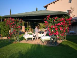 巴尼奥维尼奥尼Relais Osteria Dell'Orcia的站在花园中,种着桌子和鲜花的人