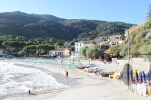 ZancaCasa Miclara - Bilocale Limoni的站在海滩上的人,有椅子和冲浪板