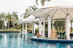 董里Rua Rasada Hotel - The Ideal Venue for Meetings & Events的度假村的游泳池,在水中配有遮阳伞