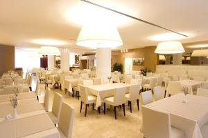 格拉多歌德拉古纳宫酒店的用餐室配有白色的桌椅和灯光