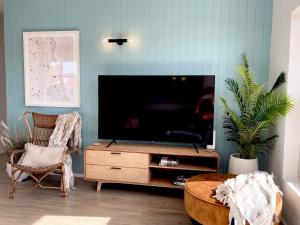 撒马佛Seabreeze at Semaphore #8 - On the Esplanade的木质娱乐中心设有带平面电视的客厅。