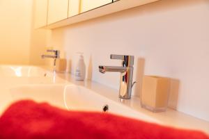 洛豪Bodenseedomizil的浴室水槽配有水龙头和红色毛巾