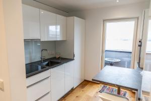 洛豪Bodenseedomizil的厨房配有白色橱柜、水槽和窗户。