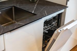 洛豪Bodenseedomizil的厨房配有开放式洗碗机,厨房配有黑色台面