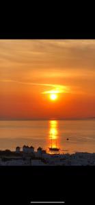 米克诺斯城伊比酷斯精品酒店的海上的日落,在水中乘船