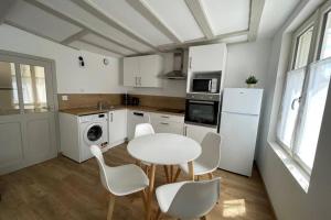拉瓦勒Centre-ville : Maison de charme - Secteur calme的厨房配有白色的桌椅和白色的冰箱。