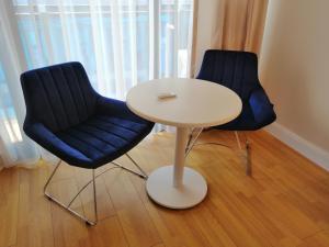 巴统Subtropik Apartments in Batumi的两把蓝色的椅子和一张白色的桌子以及一张桌子和椅子