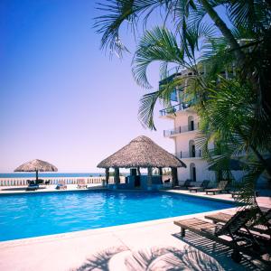 埃斯孔迪多港Hotel Caracol Plaza的棕榈树游泳池以及酒店