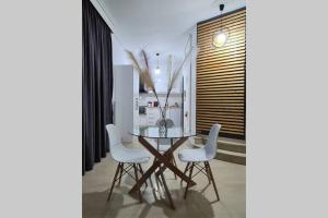 拉里萨Apartment in the heart of the city 4的一间设有玻璃桌和白色椅子的用餐室