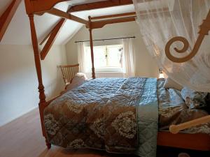 布尔坦赫城Bij de Friesche Poort的一间卧室配有一张天蓬床和窗户
