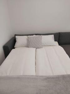 埃格尔Hello apartman的一张带白色床单和枕头的床