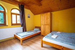 捷克布杰约维采Chata Pohoda的配有黄色墙壁和木制天花板的客房内的两张床