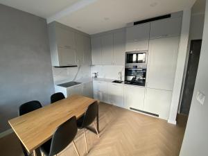 奥尔什丁Apartament Aurora的厨房配有白色橱柜和木桌及椅子