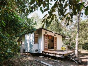 耐莉湾小树丛度假屋的树林中的一个小房子,有门廊