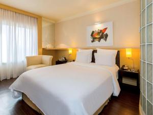 圣保罗铂尔曼圣保罗伊比拉普埃拉酒店的酒店客房设有一张白色大床和椅子