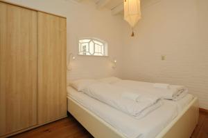 诺德克豪特Holiday home het Zeepaardje的一间卧室配有一张带白色床单的床和一扇窗户。