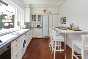 诺德克豪特Holiday home het Zeepaardje的厨房配有白色橱柜和桌椅