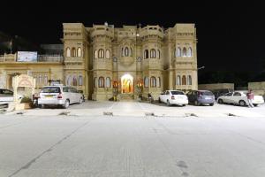斋沙默尔Hotel Lal Garh Fort And Palace的一座大型建筑,前面有汽车停放